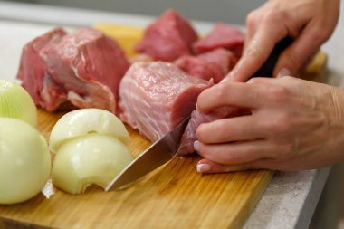 Cook bir ahşap tahta üzerinde büyük parçalar halinde çiğ et keser