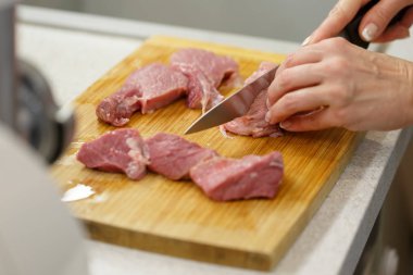 Cook bir ahşap tahta üzerinde büyük parçalar halinde çiğ et keser