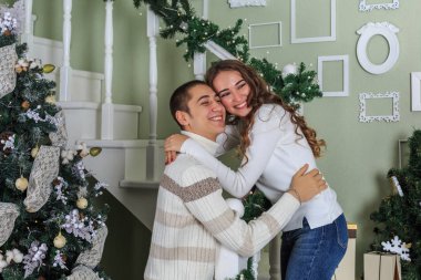 Aşık çift evde beyaz merdivenlerde duran ve her diğer Noel tatili arifesinde sarılma.