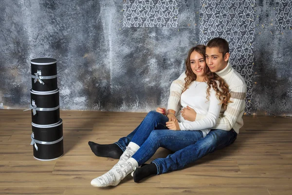 Couple of young people in love, hugging, sitting on the floor and smiling