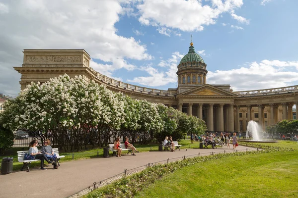 stock image RUSSIA, SAINT-PETERSBURG, 30 MAY 2018: View on the Kazan Cathedral, flowering bushes of beautiful flowers, resting people on a sunny spring day