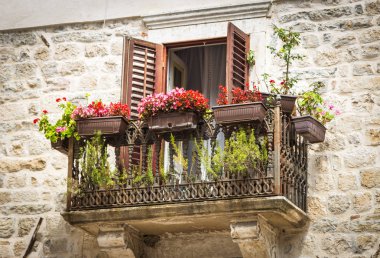 Ajur metal parmaklıklar, Kotor, Karadağ için kırmızı çiçeklerle süslenmiş güzel vintage balkon