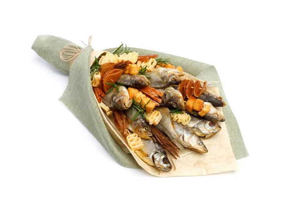Bouquet consisting of salted stockfish of different breeds, slices of dried squid and other fish lies on a white surface