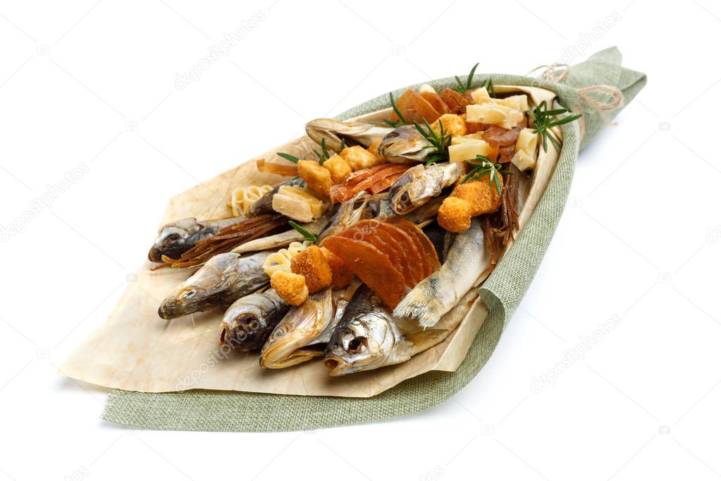 Bouquet consisting of salted stockfish of different breeds, slices of dried squid and other fish lies on a white surface. Close-up