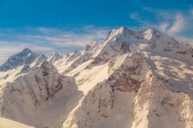 Ridge günbatımı güneşli kış gününde üzerinde şehrin Dombay, Rusya'nın Kafkasya dağlarının. Tonlu görüntü