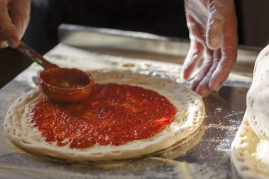 Pizza domates sosu üzerinde temel Baker yayılır. Restoranda pizza üretim