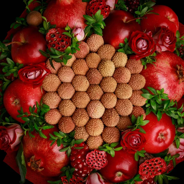 Unique homemade edible bouquet consisting of red fruits and flowers isolated on black background. Top view, close-up