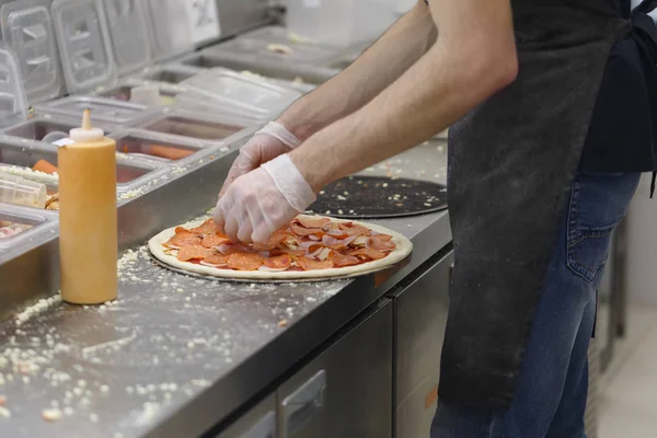 Человек Кладет Кусочки Салями Пиццу — стоковое фото