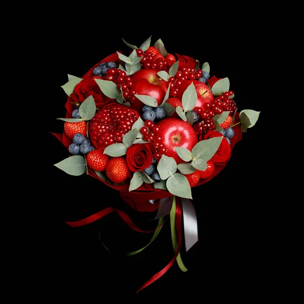 Beautiful bright red edible bouquet of strawberries, pomegranates, apples, blueberries and roses on a black background