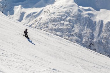 Dombay, Rusya, 27 Şubat 2018: Snowboarder rides bir dik kayak yamacında bir güneşli kış gününde
