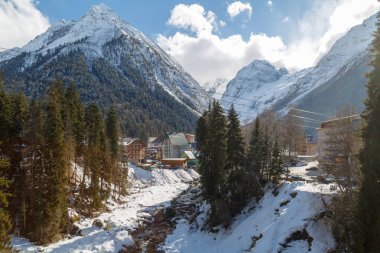 Dombay, Rusya, 28 Şubat 2018: Dağ nehir ve otel görünümünü Kafkas Dağları kış güneşli günde arka plan üzerinde