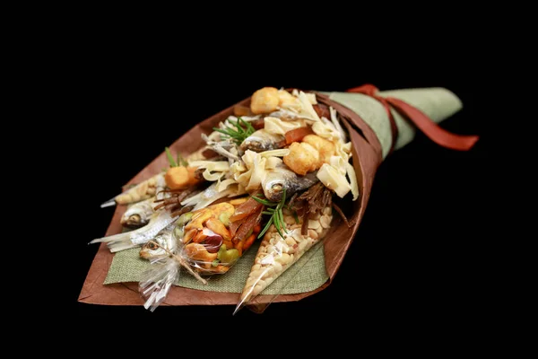 Original bouquet consisting of dried salted fish, salted peanuts, crackers, dried bread and other beer snacks isolated on black background as male gift