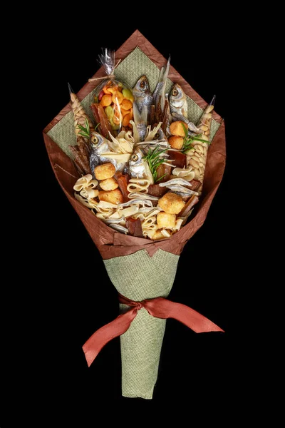 Original bouquet consisting of dried salted fish, salted peanuts, crackers, dried bread and other beer snacks isolated on black background. Top view
