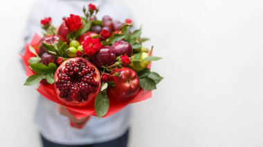 Nar, elma, üzüm, Erik ve kırmızı güller beyaz zemin üzerinde bir kadının elinde bir tebrik kartı için boş olarak oluşan güzel buket