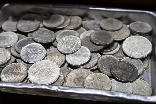 Pile of metal coins of different denominations and different countries in metal box