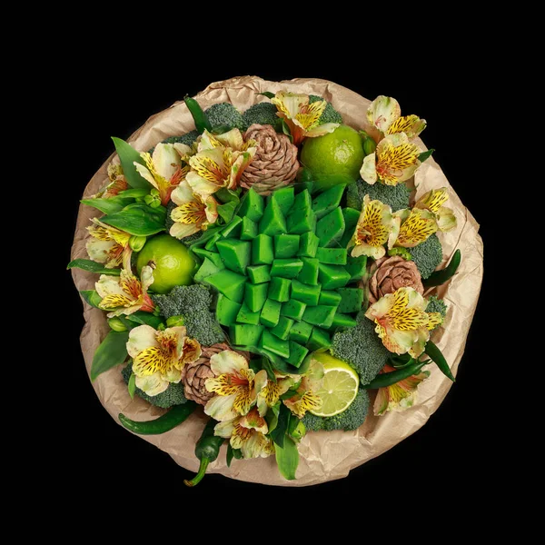 Original gift in the form of a bouquet of flowers, vegetables and green cheese, standing in a glass vase isolated on a black background. Top view