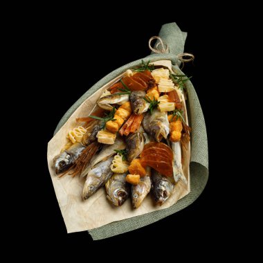 Kuru balık ve çeşitli aperatifler siyah bir arka planda izole bir buket şeklinde gerçek bir adama hediye