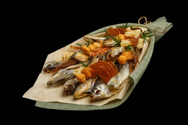 Unique edible bouquet consisting of dried fish, crackers, dried squid isolated on black background