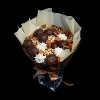 Çikolata, şekerleme, çikolata ve diğer ağız sulandıran tatlılar Marshmallows, bir buket olarak paketlenmiş, siyah bir arka plan üzerinde cam bir vazo ayakta
