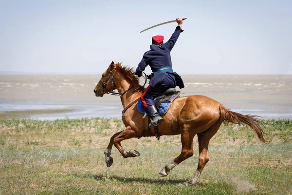 Don Kazak elinde bir kılıç ile bir at üzerinde deniz kıyısında hızlı sürmek