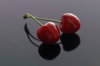 Koyu parlak arka planda bir şube üzerinde tatlı bir kiraz iki Olgun çilek