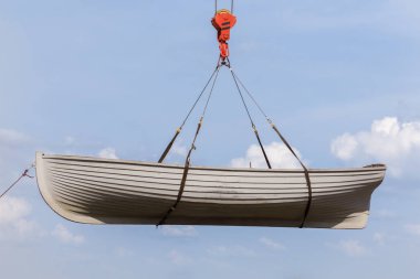 Mavi gökyüzü arka plan üzerinde bir vinç kanca asılı kürek tekne