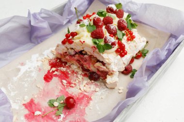 Kiraz, kırmızı kuş üzümü ve nane yaprakları ile ahududu ile Hassas beze pasta bir tepsi üzerinde