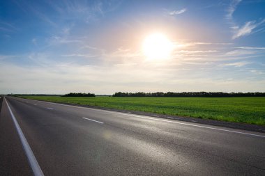 Gün batımında parlak güneşe karşı boş asfalt karayolu