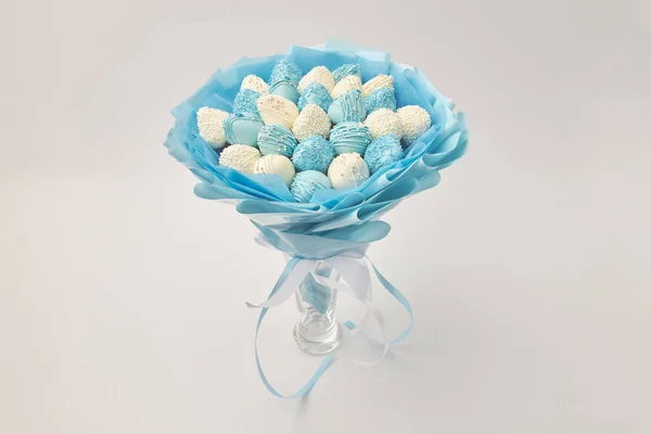 Delicious bouquet of strawberries covered with white and blue chocolate on a white background