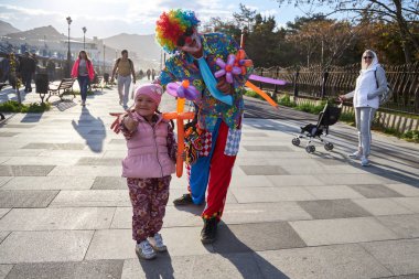 Sudak, Rusya, 02 Mayıs 2019: Parlak renkli elbiseli palyaço şirin çocuğa bir balon çiçeği verdi