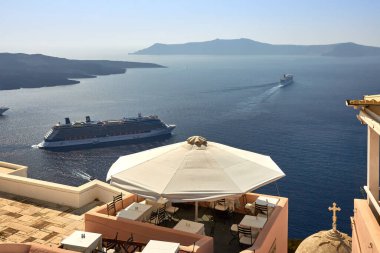 Oia, Santorini, Yunanistan, 21 Ağustos 2013: Dağların, mavi denizin ve gelen yolcu gemilerinin güzel manzaralı rahat bir kafe