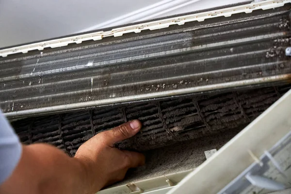 Bir servis çalışanı havalandırmanın kapalı bir ünitesinden kirli bir türbin çıkarıyor.