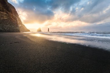 Reynisfjara ya da daha çok bilinen adıyla Kara Kum sahili gün doğumunda manzarası