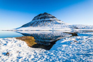 Kirkjufell, İzlanda 'nın Snaefellsnes yarımadasının kuzey kıyısında, Grundarfjordur kasabası yakınlarındaki yüksek bir dağ olan kış karları sırasında manzaraya sahiptir. 