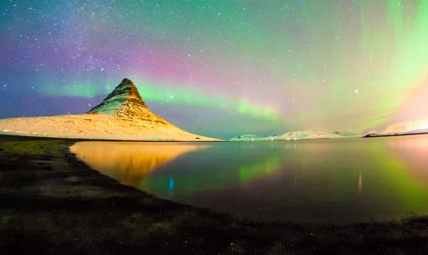 Colorful Aurora Borealis or better known as The Northern Lights and winter milky way over Kirkjufell, Iceland