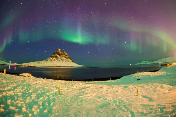 Colorful Aurora Borealis or better known as The Northern Lights and winter milky way over Kirkjufell, Iceland