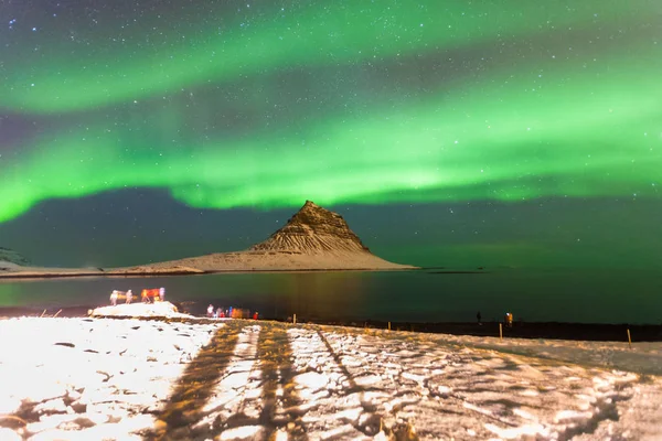 Colorful Aurora Borealis or better known as The Northern Lights and winter milky way over Kirkjufell, Iceland