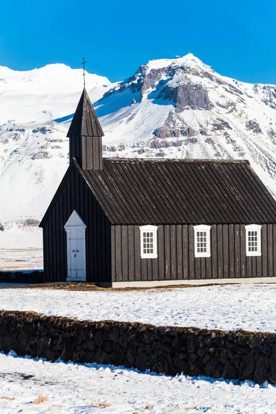 在冰岛 冬季大雪期间 布达基卡 Budakirkja 或更有名的 黑色教堂 Black Church 在蓝天下的景象 — 图库照片