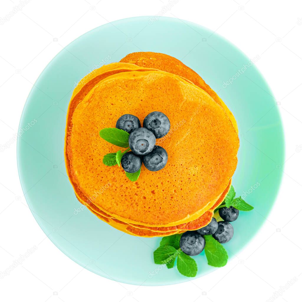 Heap of pumpkin pancakes with blueberries and mint on turquoise plate isolated on white