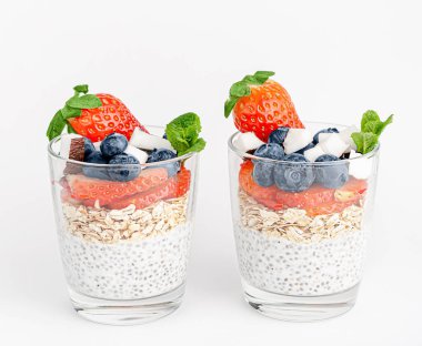 Beyaz arka planda yulaflı Chia pudingi, hindistan cevizi, çilek ve yabanmersini. Sağlıklı yemek.