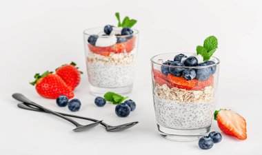 Beyaz arka planda yulaflı Chia pudingi, hindistan cevizi, çilek ve yabanmersini. Kahvaltılık tatlı.