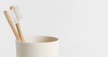 Bambu diş fırçaları beyaz arka planda, eko bardakta. Uzayı kopyala, kapat. Sıfır atık.
