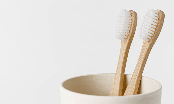 Bamboo toothbrushes in eco cup on white background. Copy space, close up. Ecological materials concept.