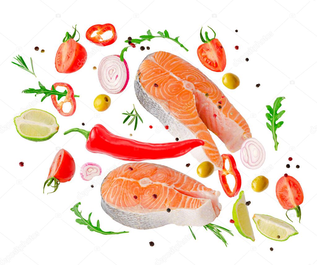 Raw steaks of salmon fish flying with vegetables, spices and herbs isolated on white background.