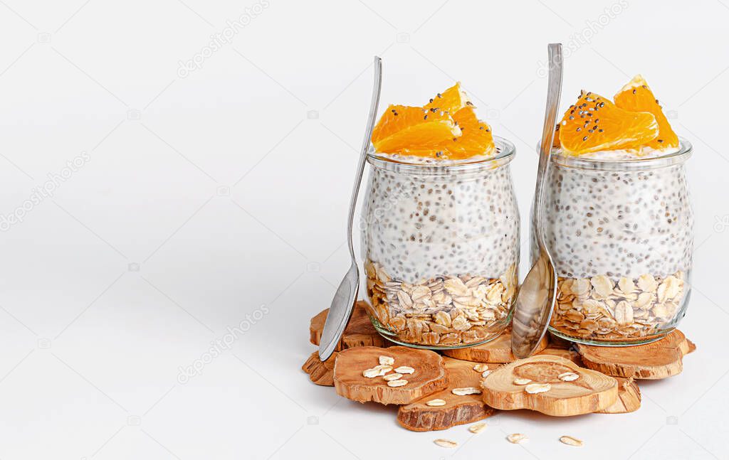 Chia seed pudding with orange and oats on white background. Breakfast and superfood concept. Copy space
