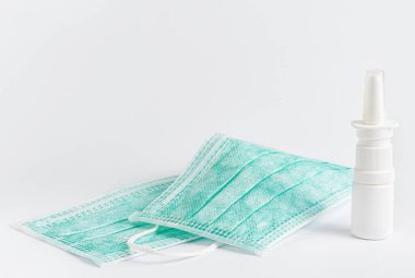 Koruyucu tıbbi maske ve beyaz arka planda burun spreyi. Boşluğu kopyala.