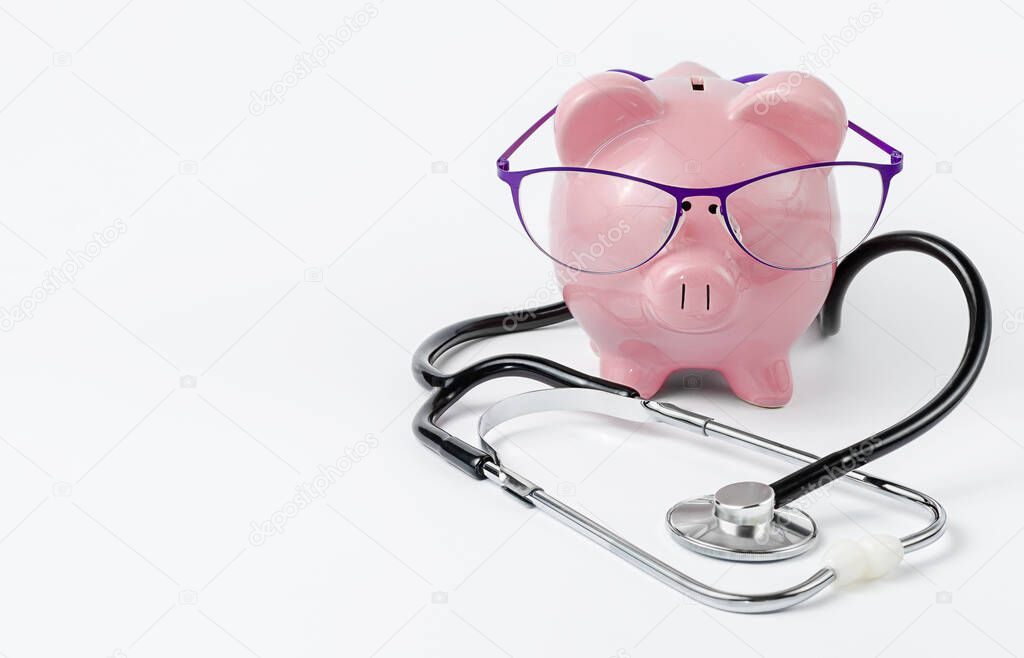 Stethoscopeand piggy bankwith glasses on white background. Medical insurance coverage concept