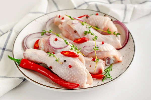 White dish with spicy marinated chicken legs or drumsticks. Raw meat and cooking concept.