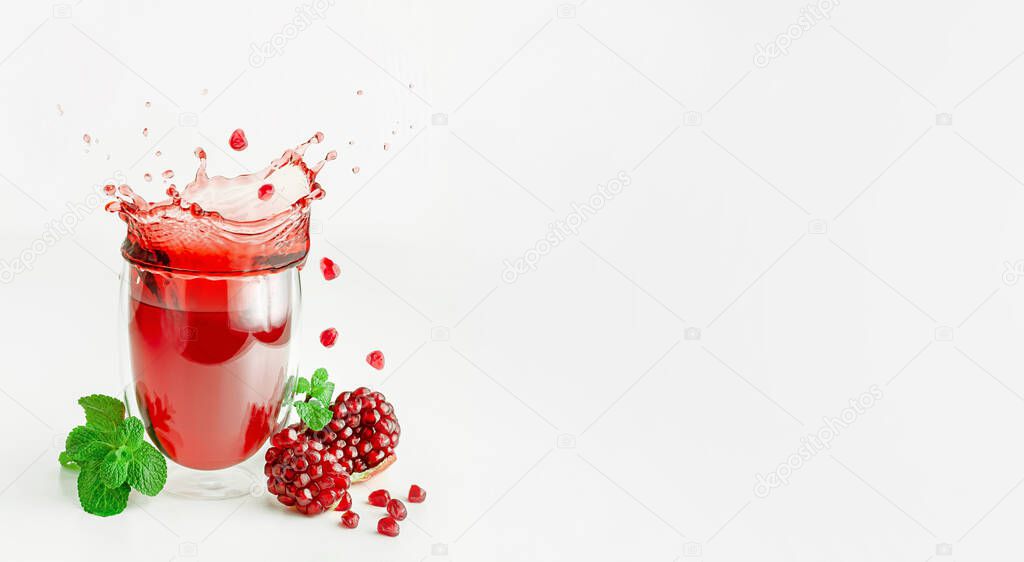 Pomegranate seeds flying over splashing fresh juice in a glass. Healthy eating and lifestyle concept.
