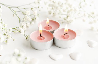 Çiçeklerle süslenmiş parfümlü mumları yakmak. Romantik arkaplan.
